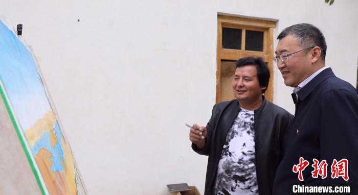 赵俊岭(右一)跟农民画家艾拜杜拉·麦提尼亚孜交流。　赵飞 摄